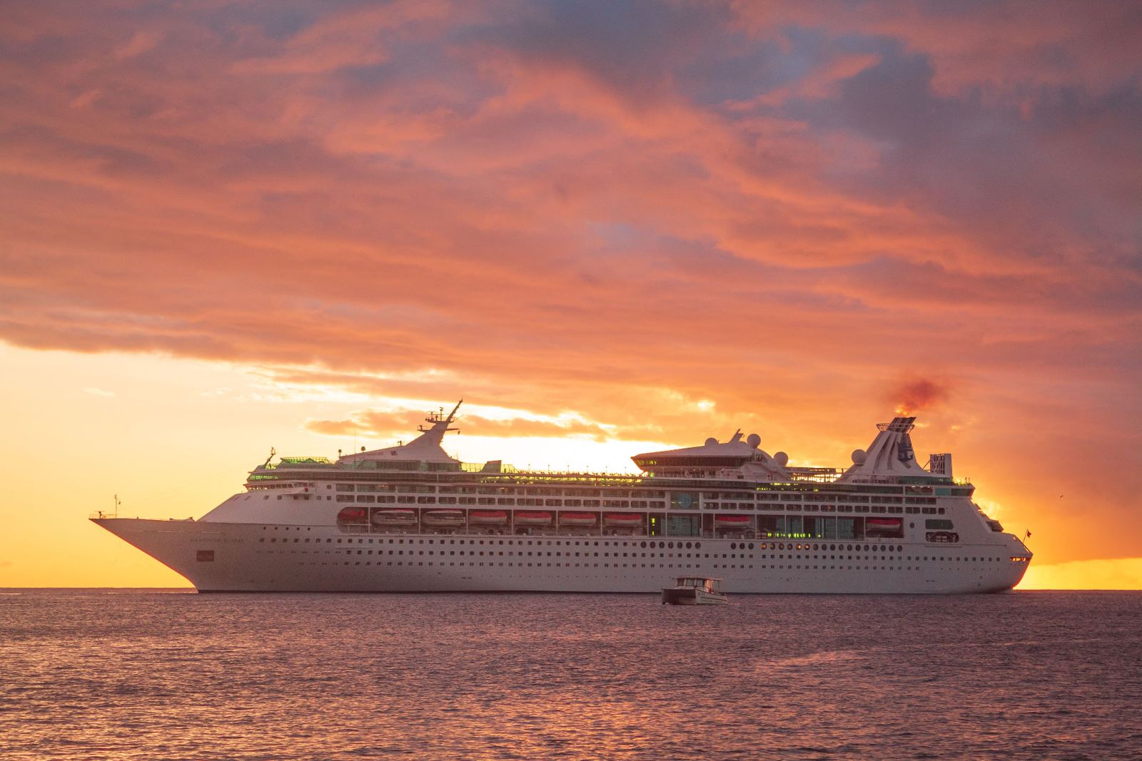 Cruise ship sailing at sunset under an orange sky